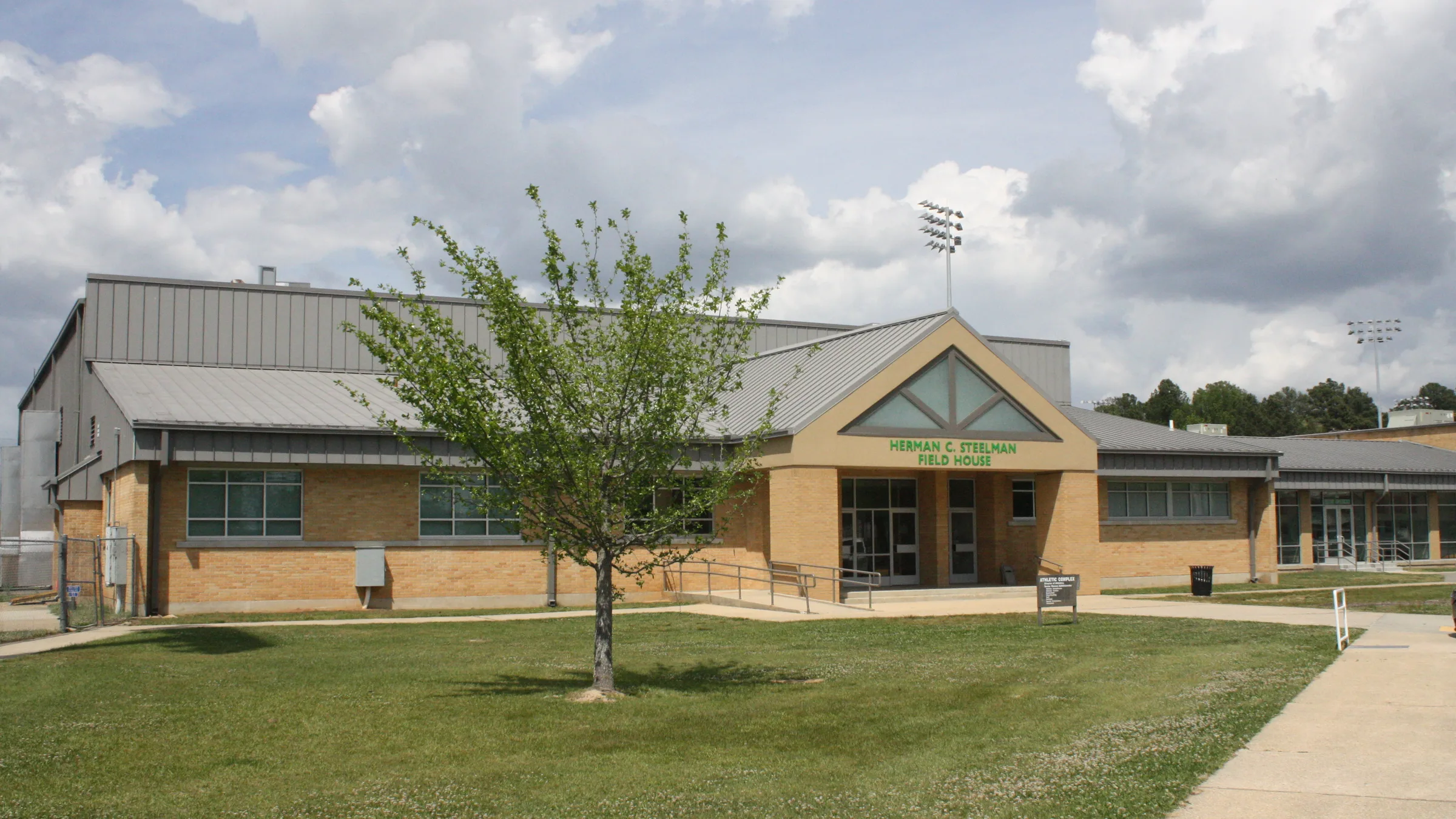 Gibson University Center on the University of Arkansas at Monticello campus, a tan building with an angled metal roof and the center name on the front.